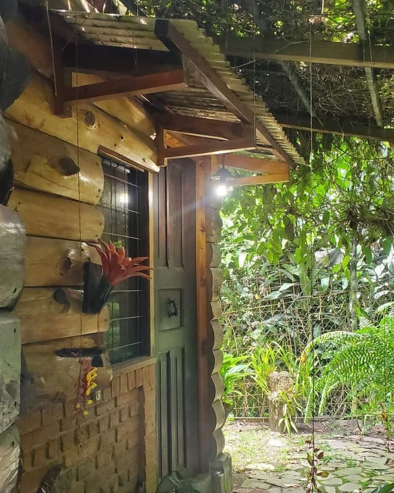Puerta de entrada de la cabaña bajo enramada y plantas en Tu Jardín Secreto