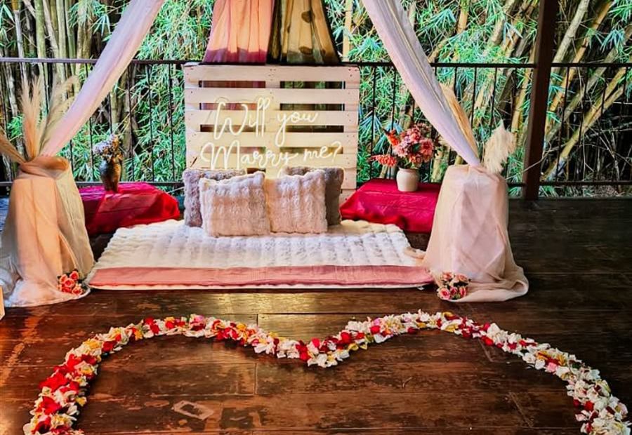 Montaje tepee para propuesta de noviazgo con tela blanca, luces y corazón de pétalos
