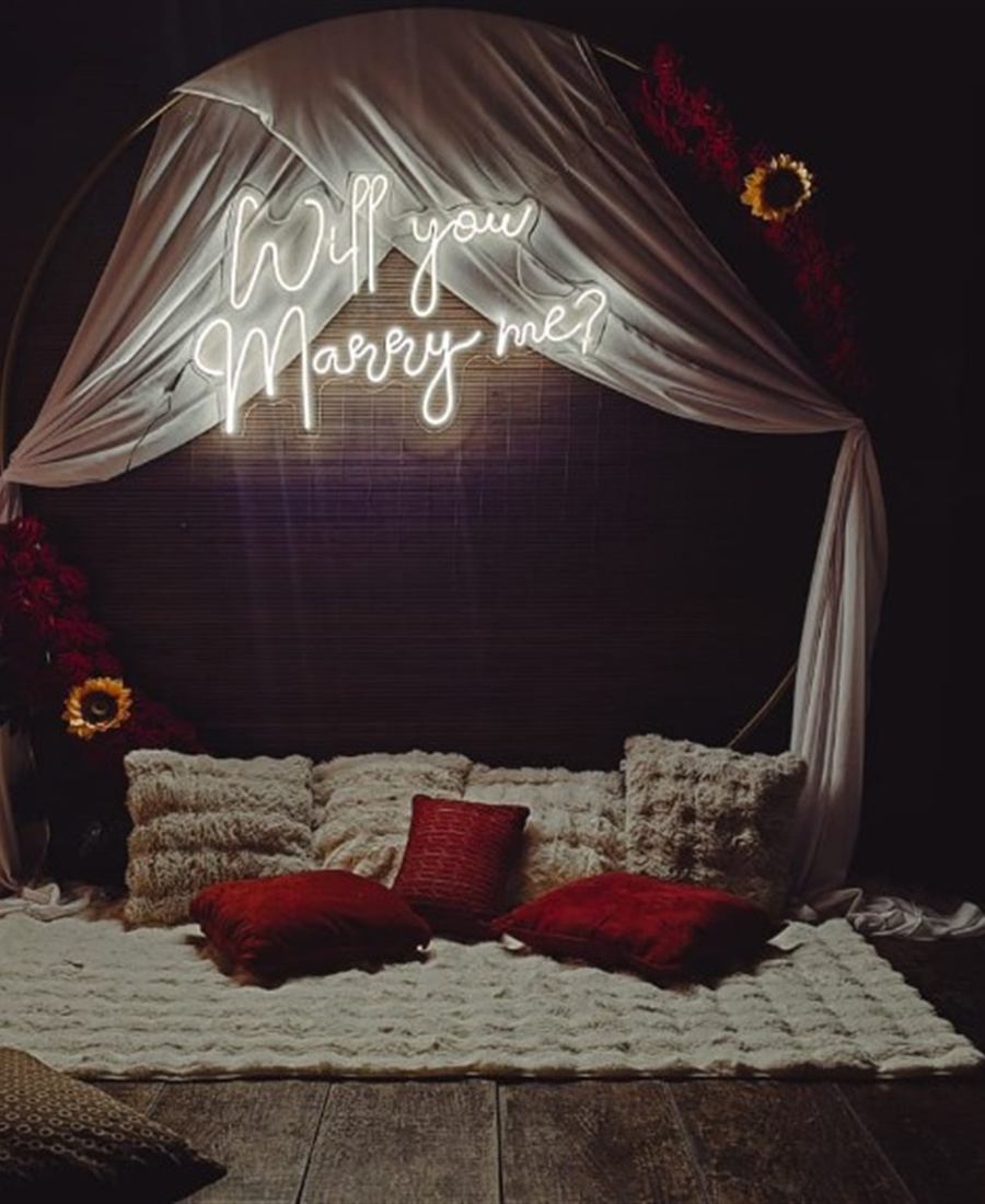 Aro con tela blanca y letrero Will you marry me sobre alfombra y cojines