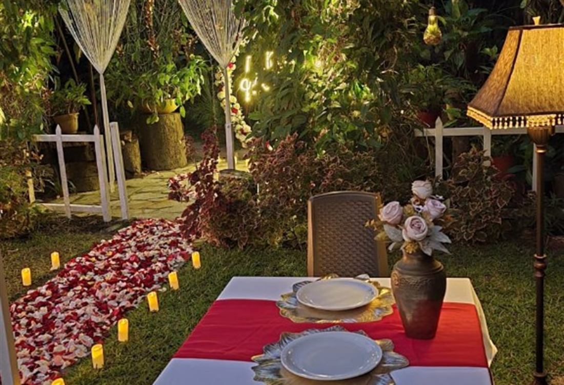 Cena íntima para dos en el jardín de Tu Jardín Secreto, Planes de Renderos, con pétalos y luces cálidas