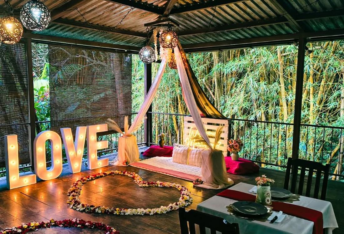 Letras LOVE, tepee y cena para dos en terraza techada rodeada de bambú