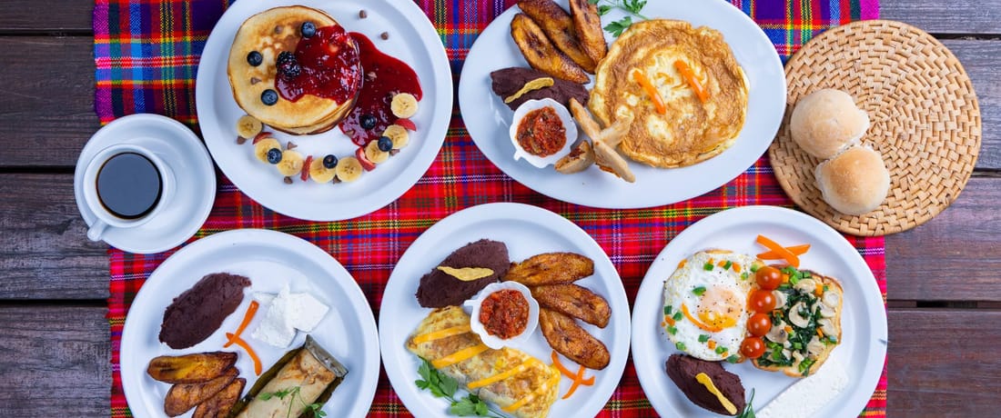Vista superior de varios desayunos típicos salvadoreños con café y pan
