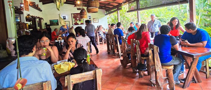 Salón techado del restaurante con mesas rústicas y vista al jardín